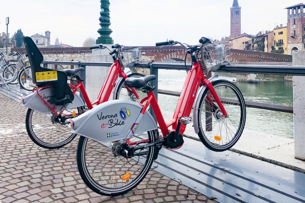 two Verona Bikes parked next to the Adige River