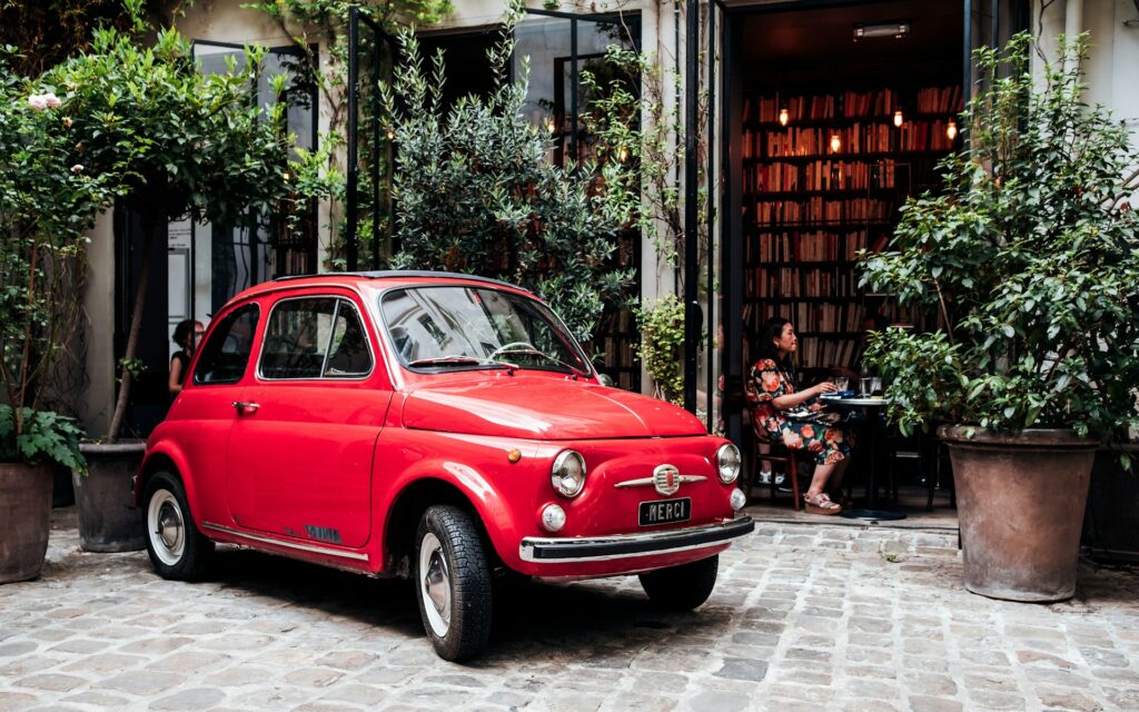 An Italian car sits outside of a caffe in Italy